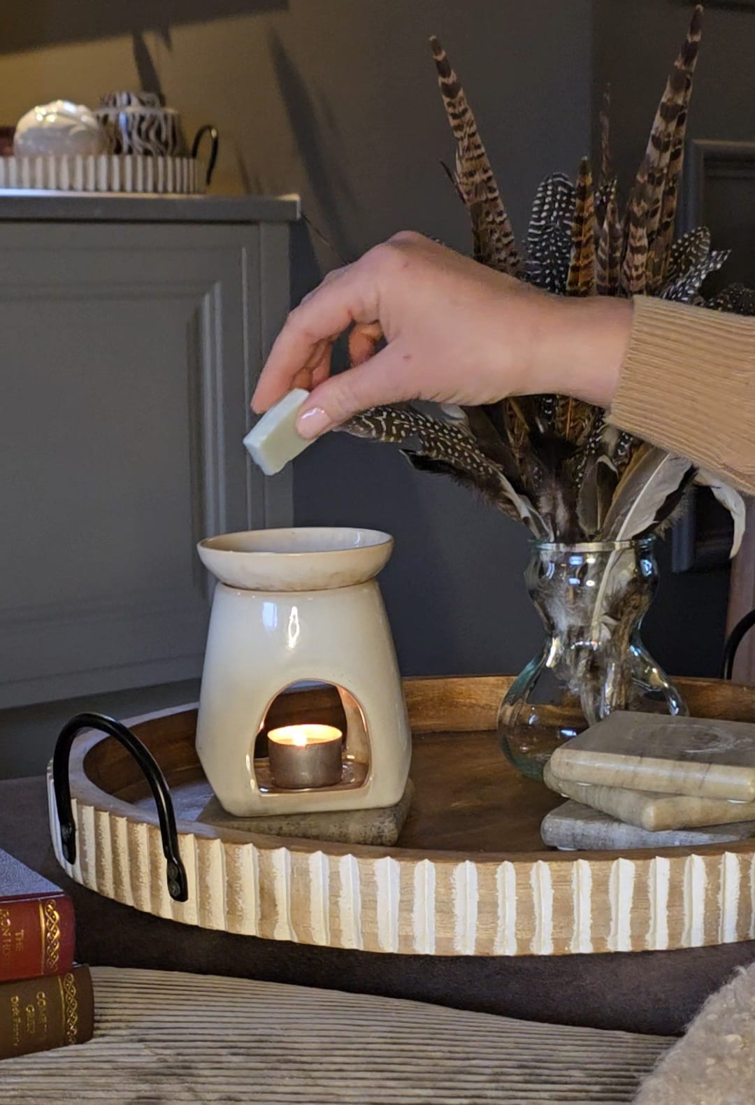 Hand placing a wax melt into a burner in a cosy living room