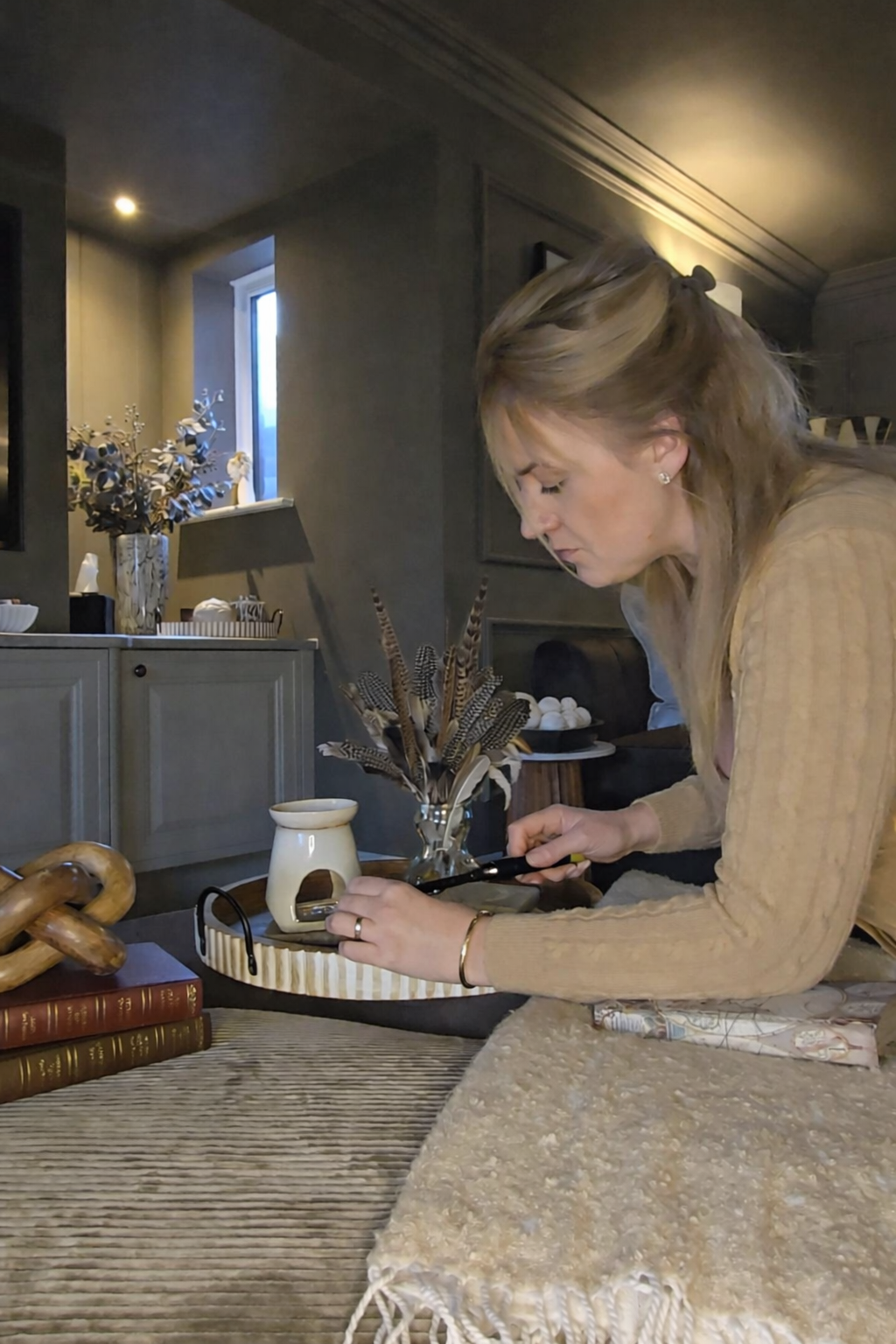 Louise lighting a wax melt burner in a cosy living room
